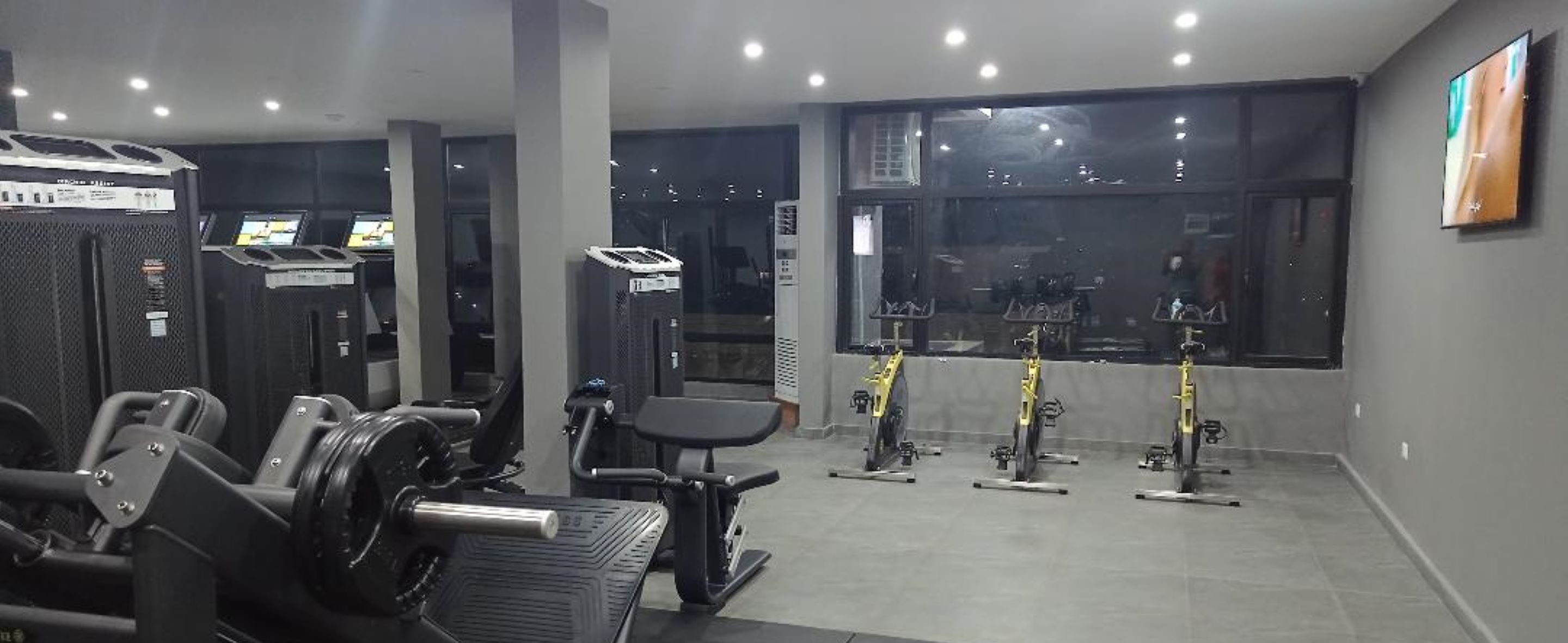 A gym with weight machines, a bench press, and stationary bikes.