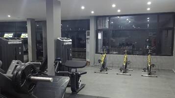 A gym with weight machines, a bench press, and stationary bikes.