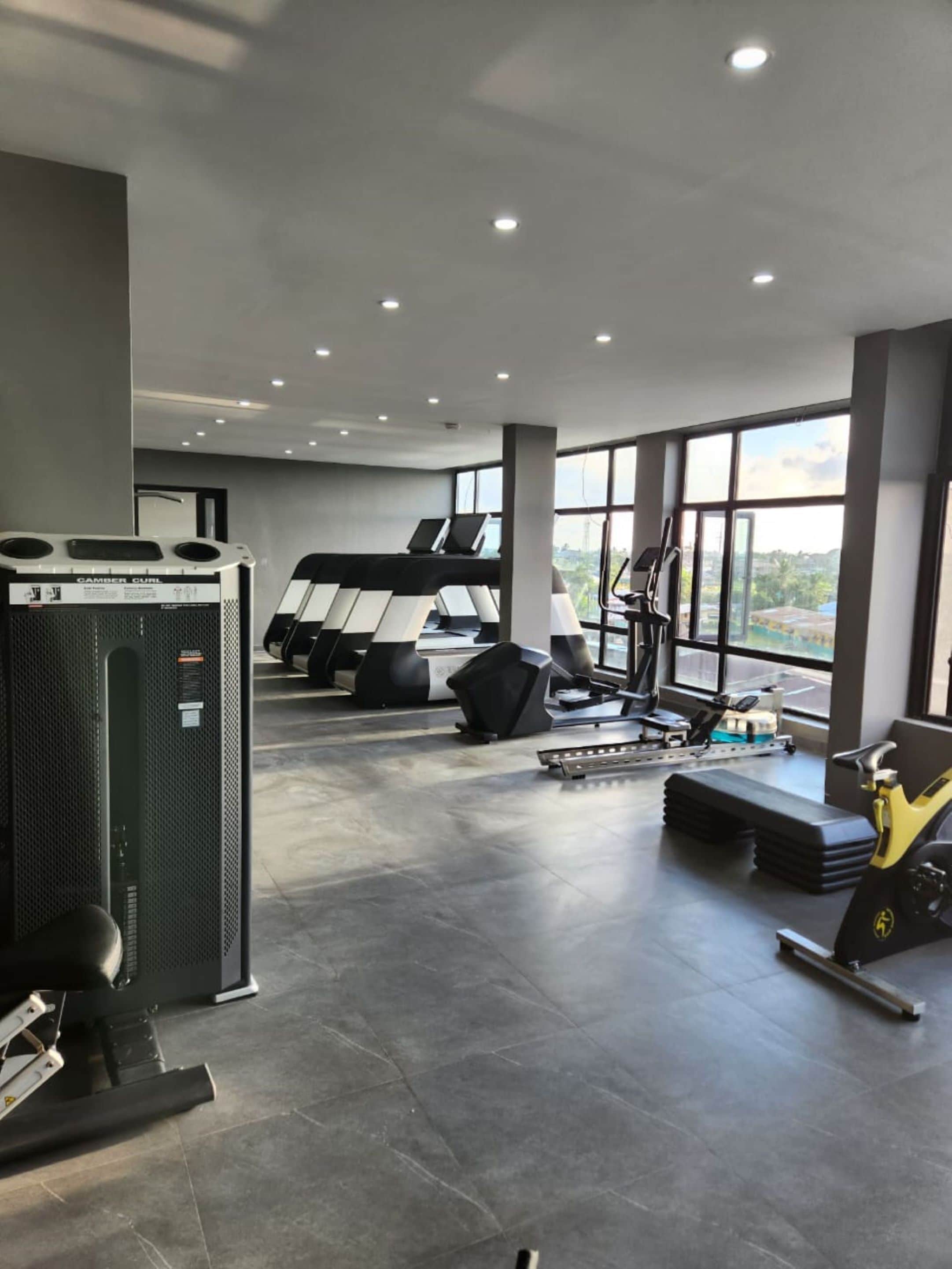 Un gimnasio con cintas de correr, una bicicleta estática y una máquina de pesas.