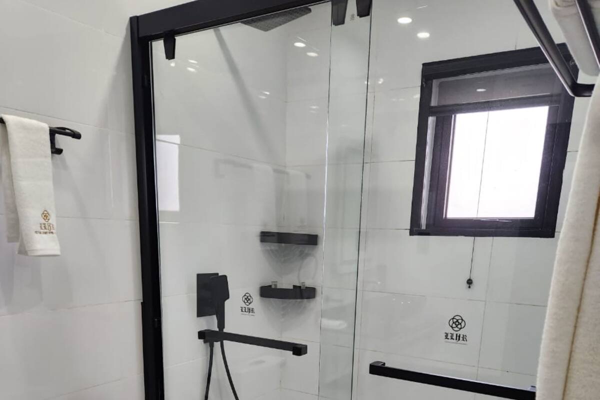 Een moderne badkamer met een douche met glazen wand, toilet en handdoekhouder.