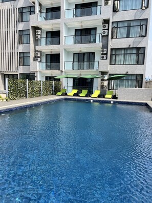 Um edifício moderno com piscina, aparelhos de ar condicionado e área externa com guarda-sóis.