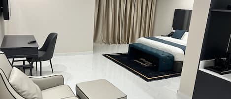 Una habitación de hotel moderna con una cama, un escritorio con una silla, un sofá y un reposapiés.