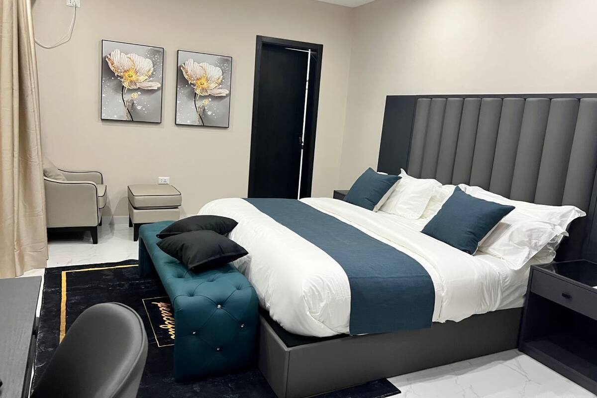 Een moderne hotelkamer met een groot bed, een bankje, een bureau en een stoel.
