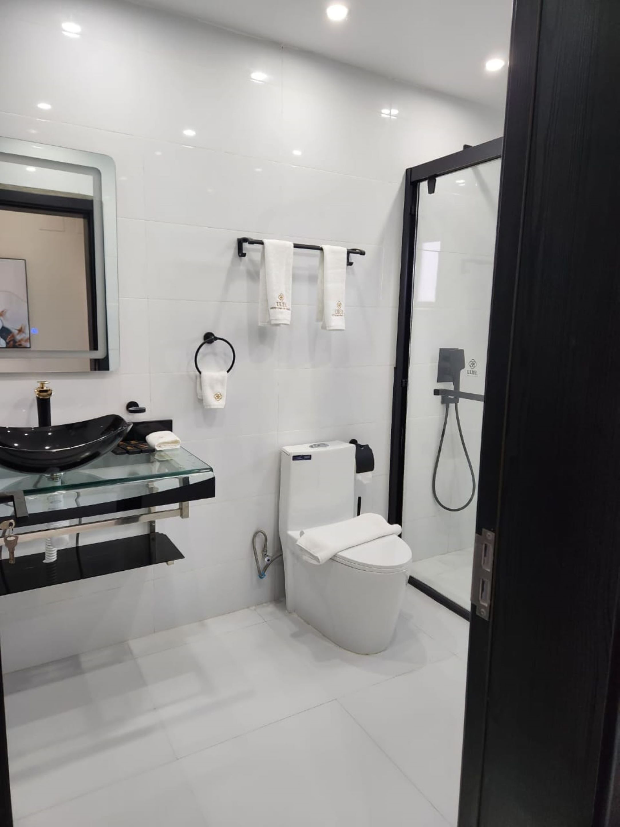 A modern bathroom with a glass sink, white toilet, and a glass-enclosed shower area.