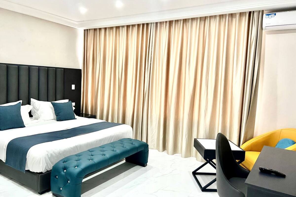 Een moderne hotelkamer met een groot bed, een bankje, een bureau en een stoel.