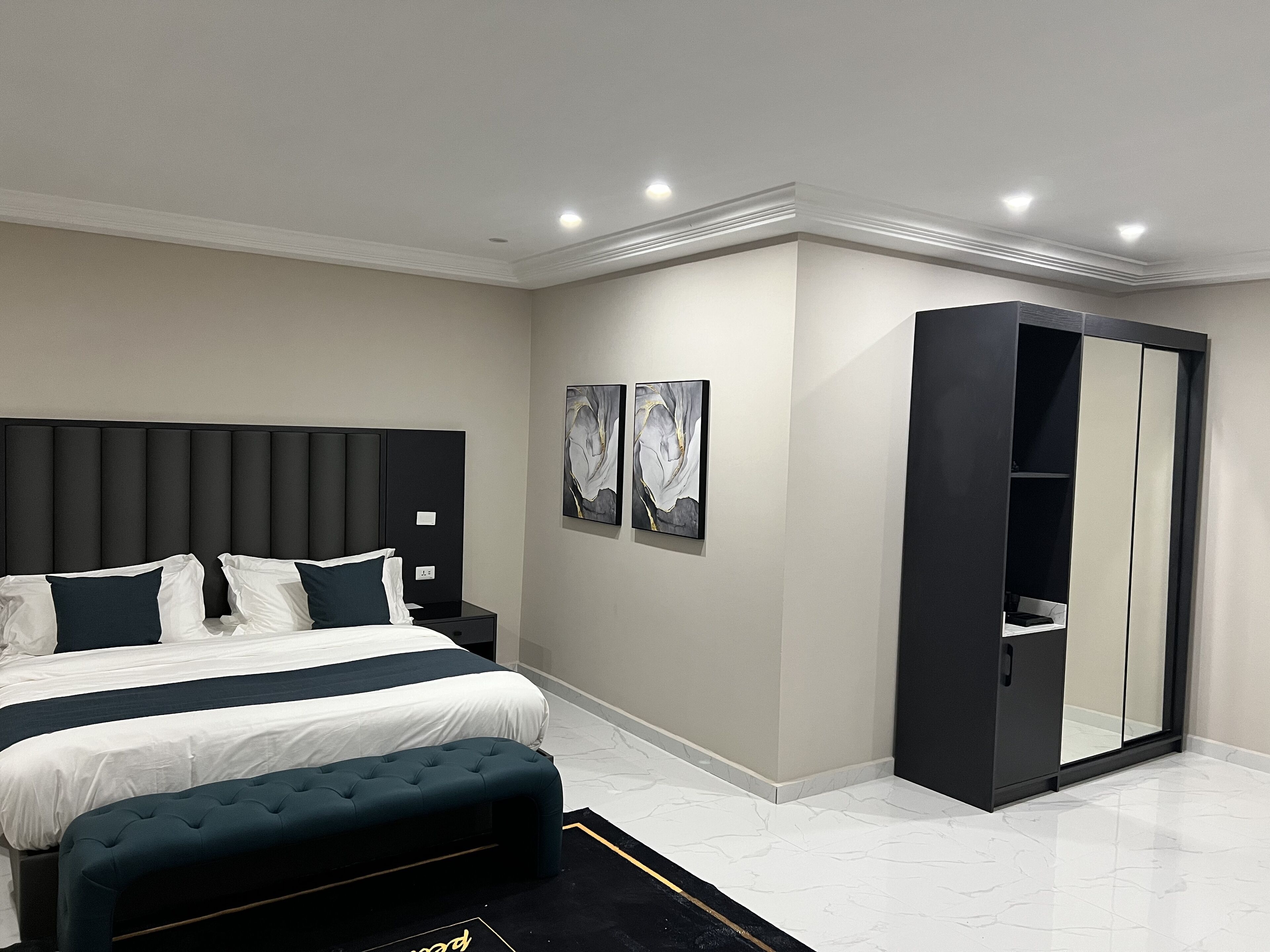 Une chambre à coucher moderne avec un grand lit, un banc et une armoire.