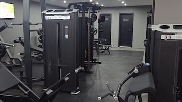 Un gimnasio con diversos equipos de ejercicio, como una barra para fondos, un rack para sentadillas y una máquina de poleas.