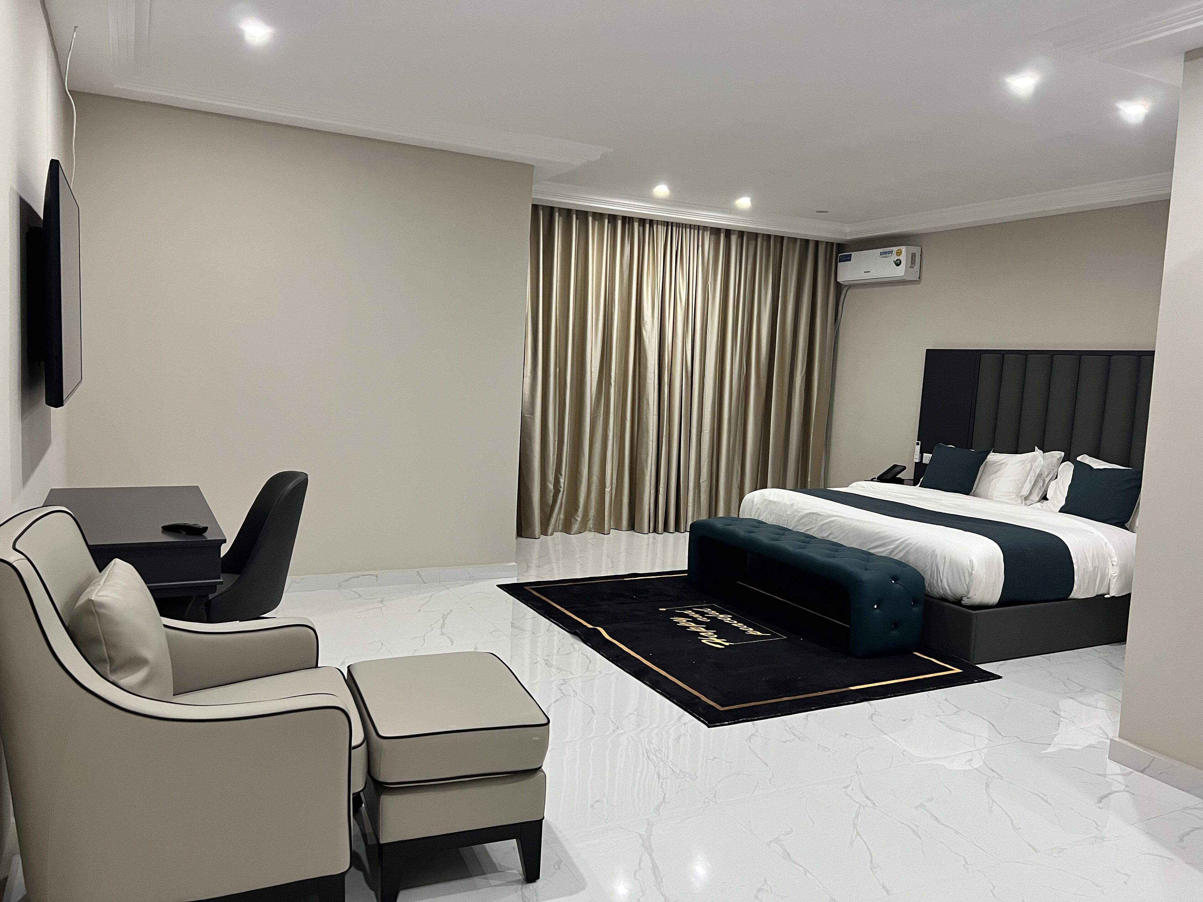 Quarto de hotel moderno com uma cama grande, uma escrivaninha, uma cadeira e uma televisão de tela plana.