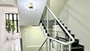 Una escalera moderna con barandillas de vidrio y un accesorio de luz geométrico.