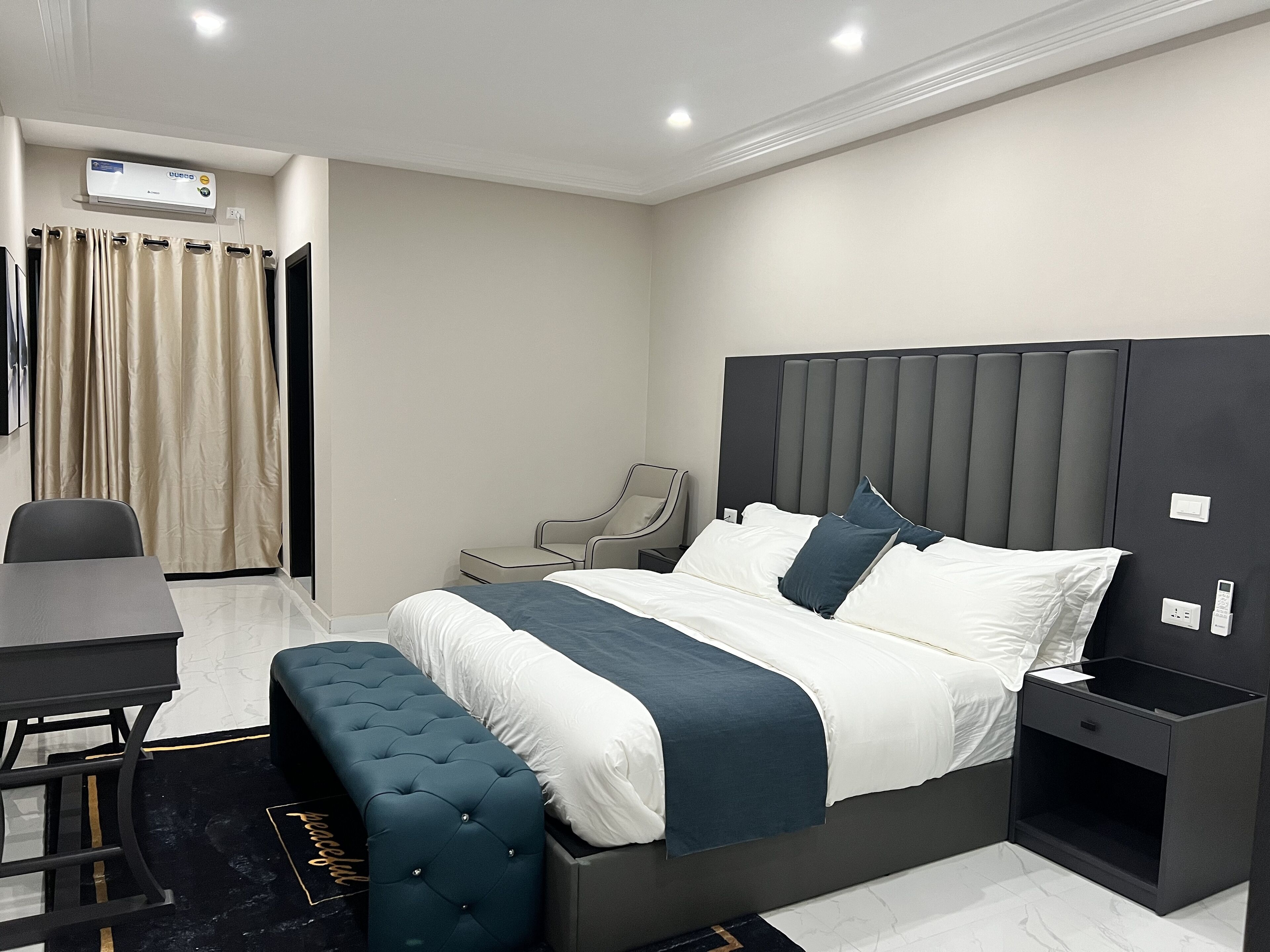 A modern hotel room with a large bed, bedside tables, a desk, and a chair.