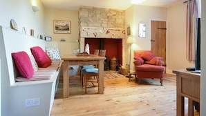 A cozy living room with a stone fireplace, wooden furniture, and a red armchair.