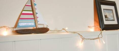 Un velero decorativo con vela a rayas y base de madera sobre una repisa.