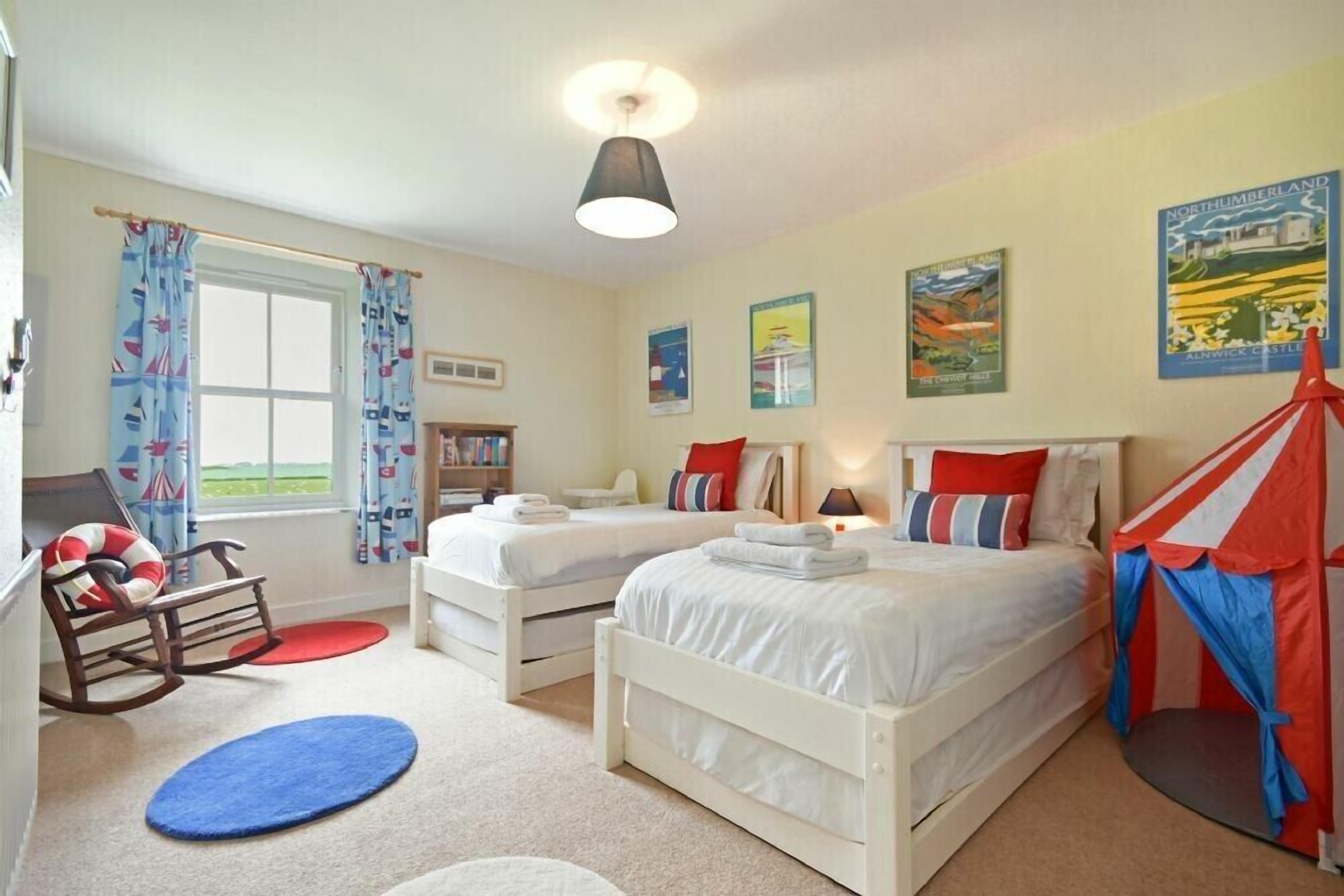A bedroom with two single beds, a rocking chair, a tent-like structure, and a window with curtains.