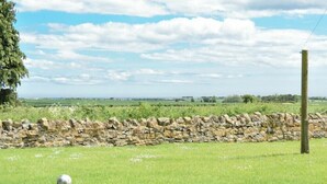 A stone wall with a grassy field and a clear sky.
