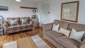 A cozy living room with two plaid sofas, a wooden coffee table, a map on the wall, and a hanging light fixture. - Beachward (Alnwick)