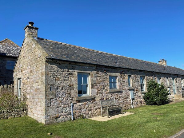 A stone building with multiple windows and a chimney.