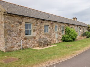 A stone building with multiple windows and a small bench in front.