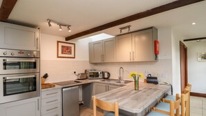 Eine moderne Küche mit eingebauten Backöfen, einer Mikrowelle, einem Spülbecken und Holzkreisen um eine zentrale Kochinsel.
