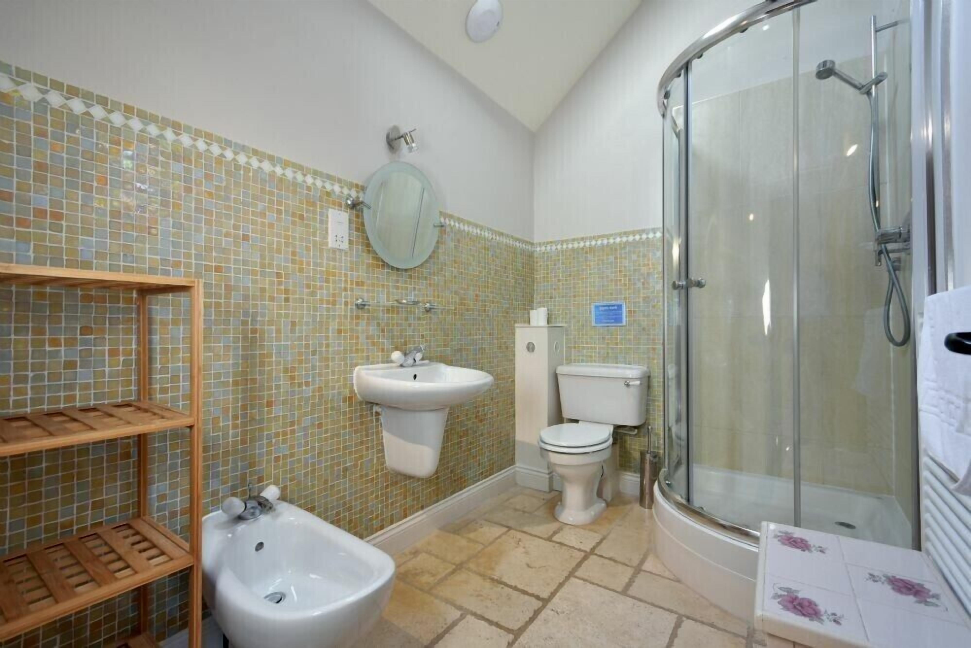 A bathroom with a shower, sink, toilet, and bidet.