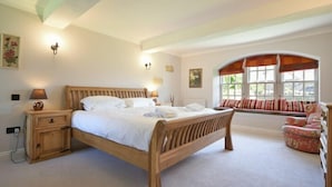 A bedroom with a wooden bed, bedside lamps, a window with curtains, and a bench by the window. - Budle Sands (Bamburgh)