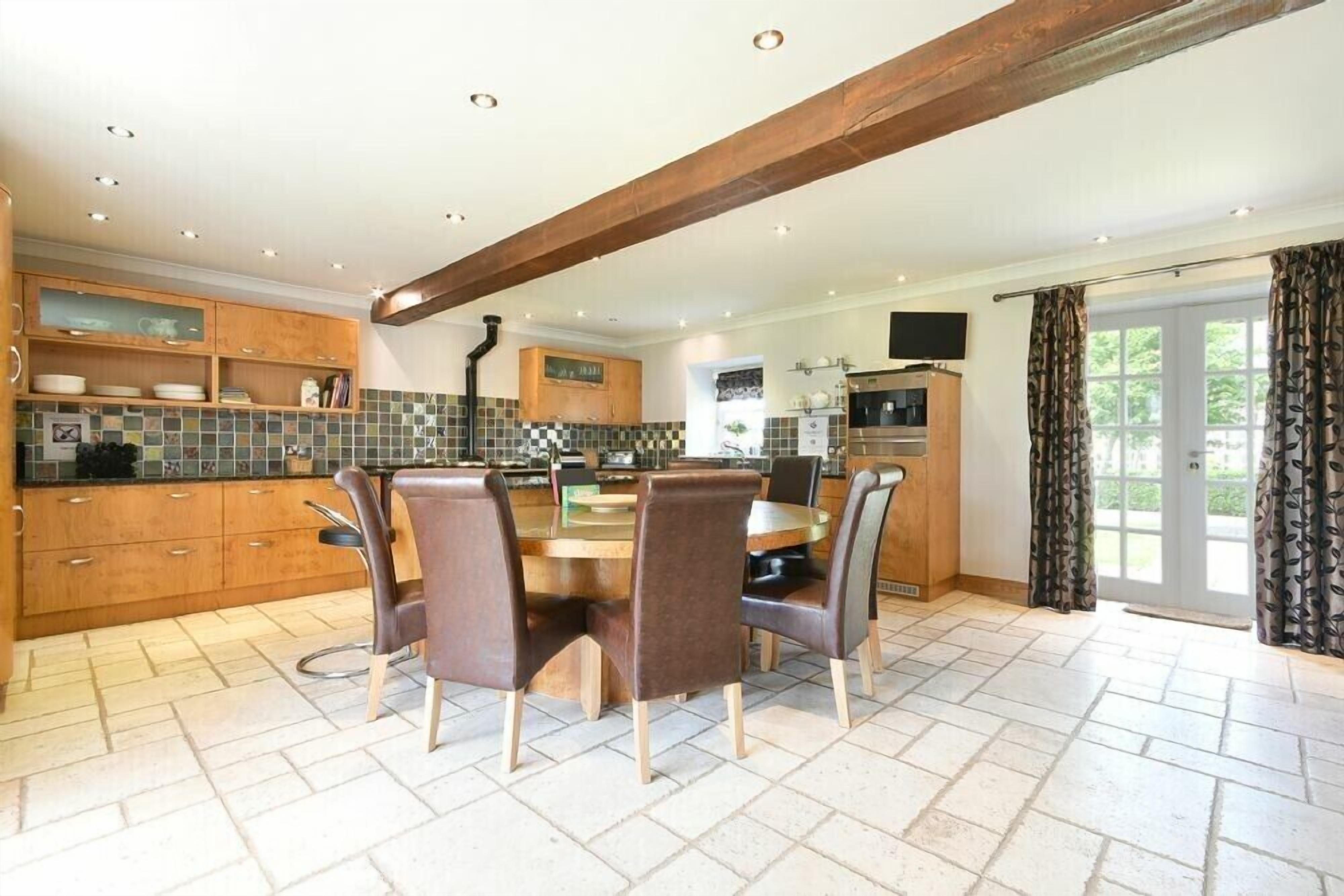 A modern kitchen with wooden cabinets, a tiled backsplash, and a dining area with a round table and chairs.