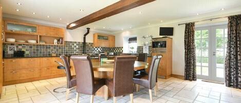 A modern kitchen with wooden cabinets, a tiled backsplash, and a dining area with a round table and chairs.