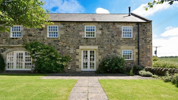 A stone building with a central entrance, two windows on the upper floor, and a small porch with a door. - Budle Sands (Bamburgh)