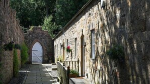 A narrow stone pathway leading to a building with a large arched entrance and multiple windows.