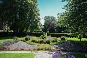 A well-maintained garden with a stone pathway, neatly trimmed hedges, and various flowering plants. - Craster Tower Coach House (Alnwick)