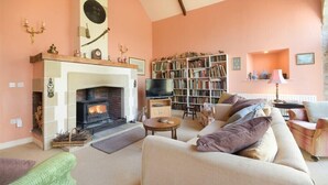 A cozy living room with a fireplace, a bookshelf, and a television.