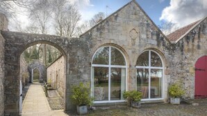 A stone building with arched windows and a red door.