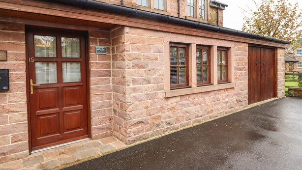 A stone building with a large wooden door and multiple windows. - Stewart House (Wooler)
