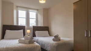 A hotel room with two beds, a window, and a wardrobe. - Stewart House (Wooler)
