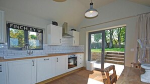 Een moderne keuken met witte kastjes, een houten aanrechtblad en een groot raam met uitzicht op een tuin.