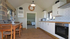 Een keuken met witte kastjes, een houten eettafel en een hanglamp.