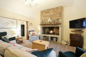 Una sala de estar con chimenea, televisor y alfombra a cuadros.