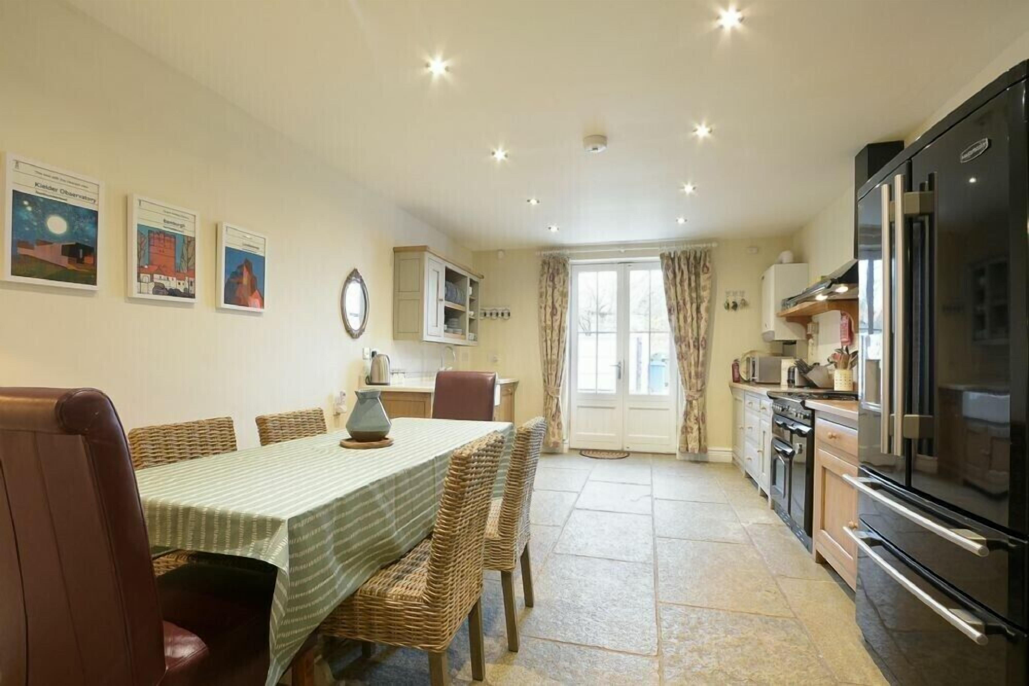 A dining area with a table and chairs, a kitchen with appliances, and a door leading to another room.
