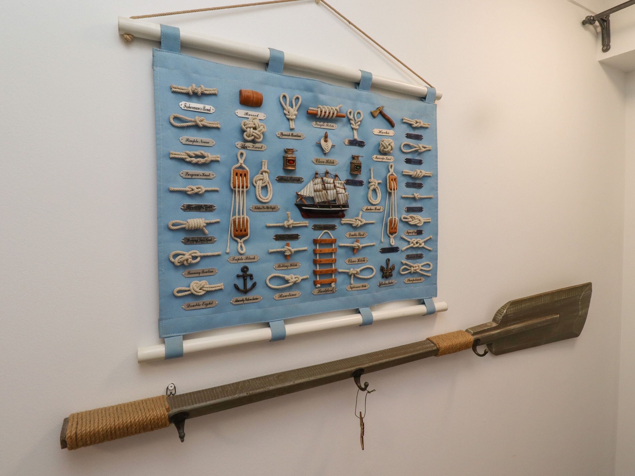 A display of various ropes and nautical equipment on a blue cloth, with a large knife hanging below.