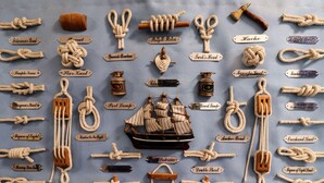 Various types of knots and maritime equipment displayed on a blue fabric background. - The Little Boathouse (Seahouses)