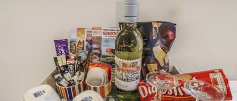 A tray with various items including a bottle of wine, wine glasses, a box of digestive biscuits, and some travel brochures.
