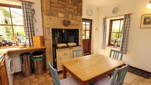 A kitchen with a stone wall, a wooden table, and blue chairs.
