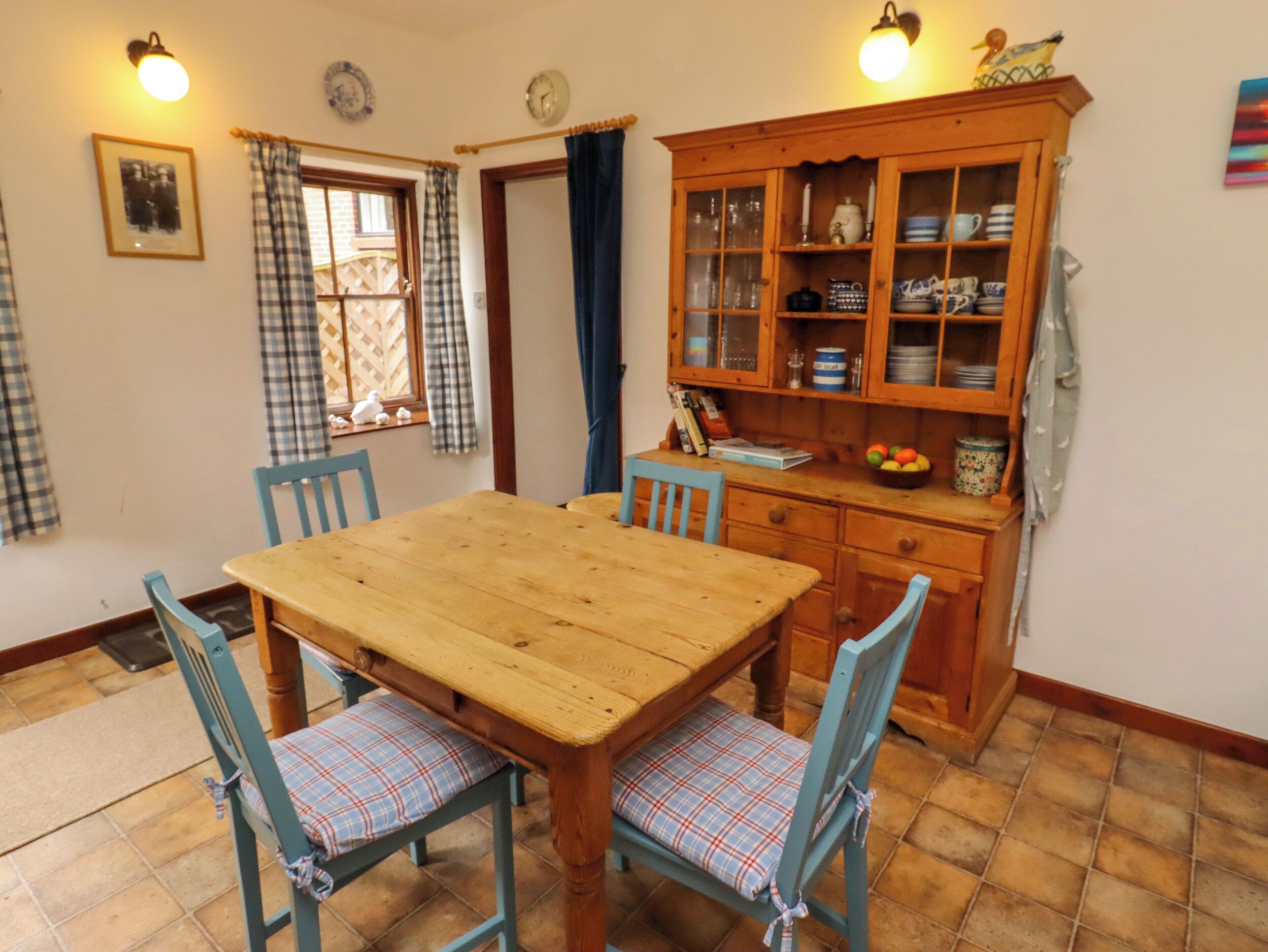 A dining area with a wooden table and chairs, a cabinet with glass doors, and a window with curtains.