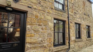 A stone building with a black door marked '17A,' windows, and a visible chimney.