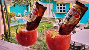 Two drinks in glasses with a lime slice, placed on a wooden table outdoors. - Hotel EbenEzer El Paredon (Sipacate)