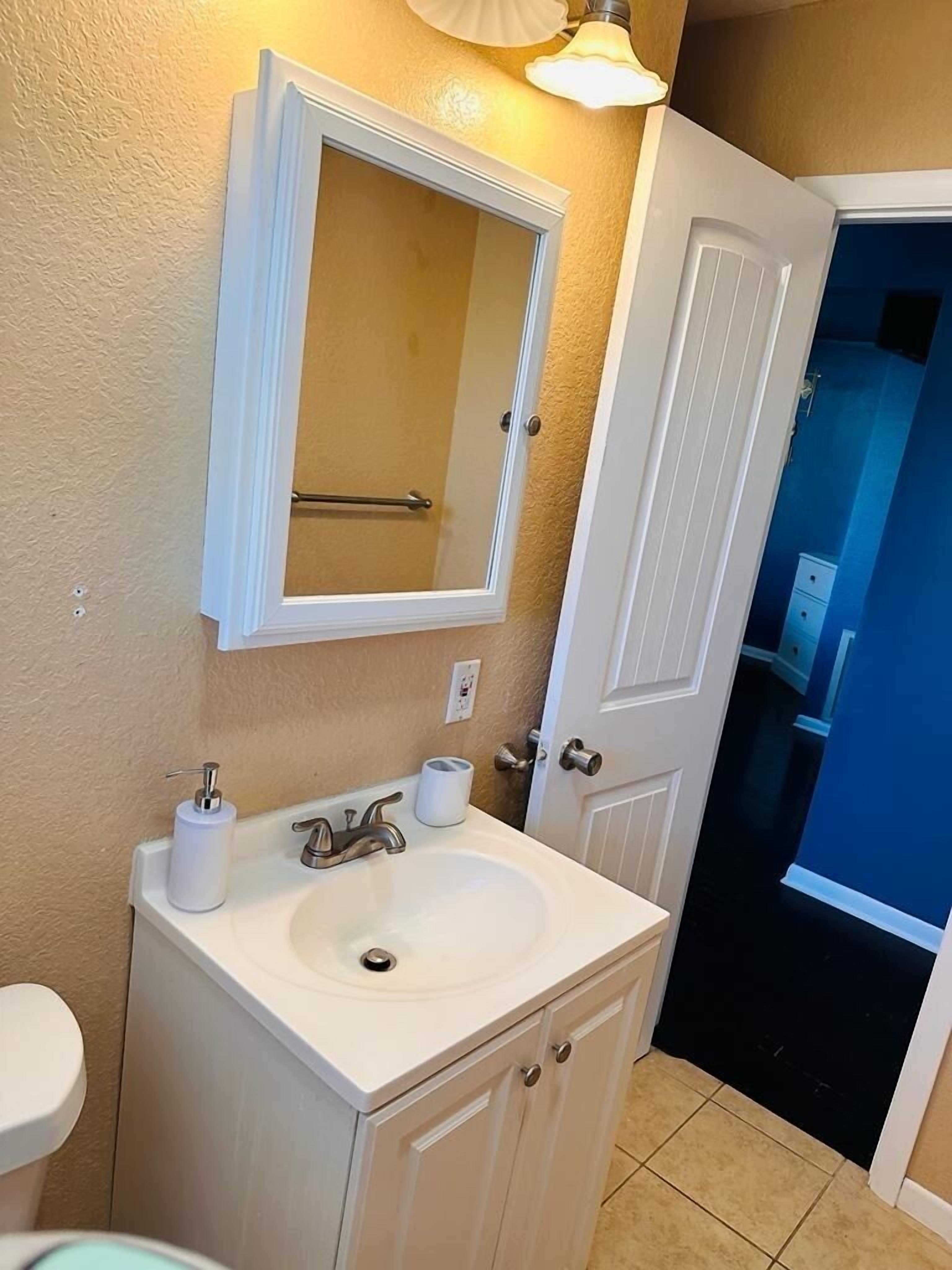 A bathroom with a white sink, a mirror, and a toilet.