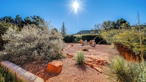 A landscaped outdoor area with a clear sky, a paved path, and outdoor furniture. - Red Rock Mtn View & Fire Pit: Central Sedona Home! (Sedona)