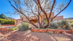 A modern building with a stone retaining wall and desert landscaping. - Red Rock Mtn View & Fire Pit: Central Sedona Home! (Sedona)