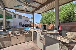 Enjoy al fresco dining with a stainless steel grill and dishwasher in this outdoor kitchen area.