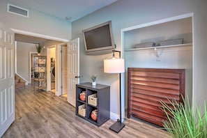 Cozy room with a television, lamp, and fireplace, featuring a wooden door and a shelf with decorative items.