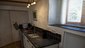 A kitchen with a sink, stove, and window with blinds.